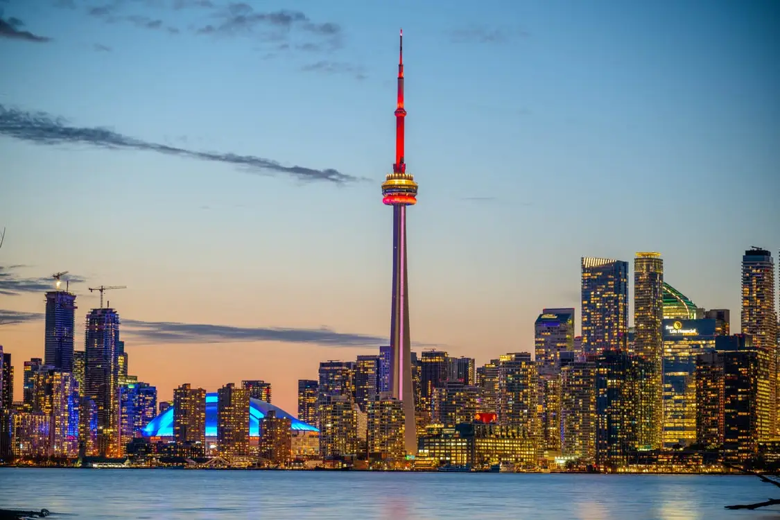 CN Tower and illuminated Toronto skyline at dusk with reflective waterfront