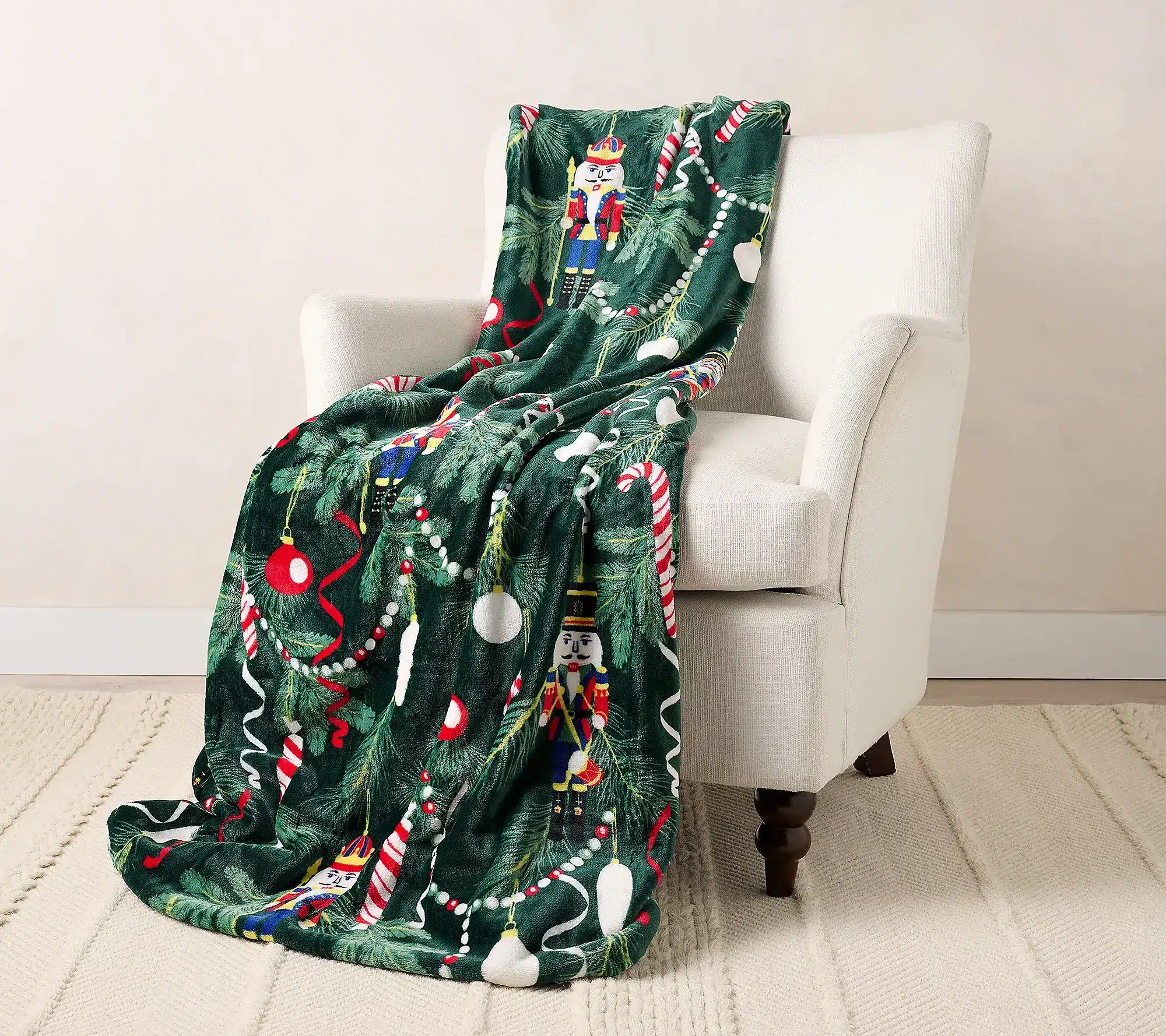 Festive green blanket with nutcracker and candy cane pattern draped over white armchair