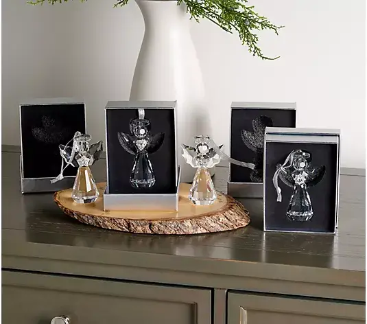 Crystal angel figurines on wooden slab with boxed packaging on a dark wooden table