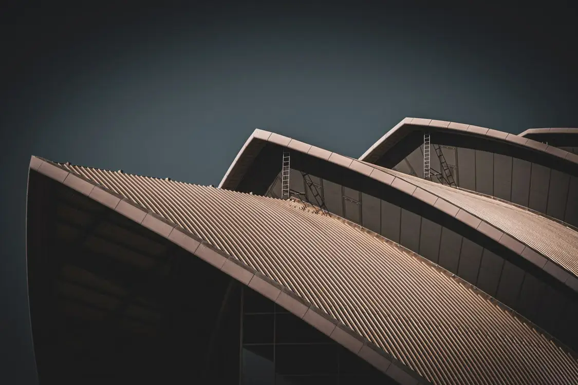 Close-up of modern architectural rooftop with abstract curves under dark sky