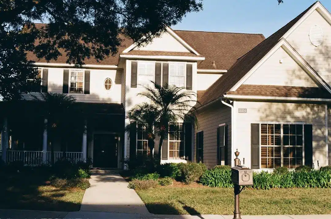 Traditional suburban house with palm trees and front porch bathed in afternoon sunlight