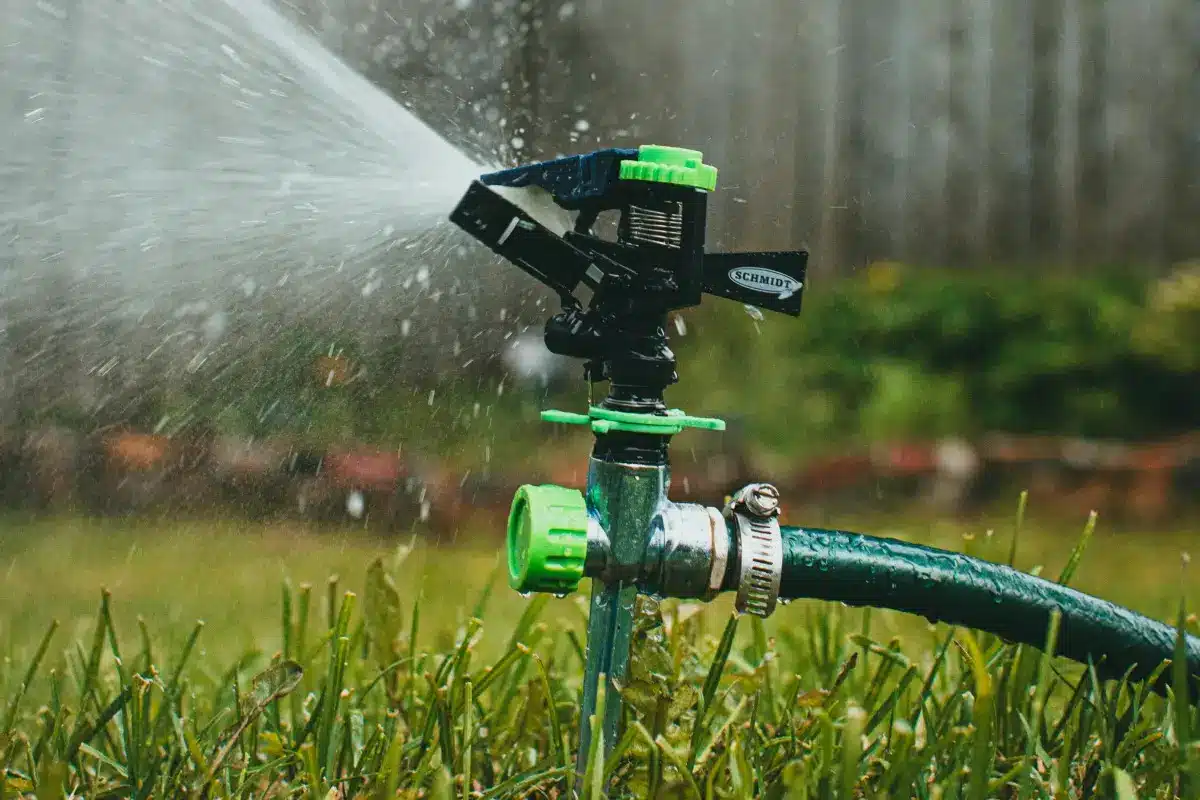 Sprinkler spraying water over green lawn in a garden setting