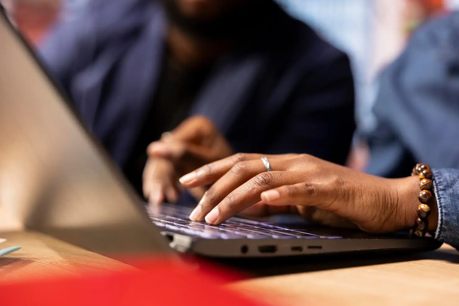 Hands typing on a laptop keyboard in an office setting