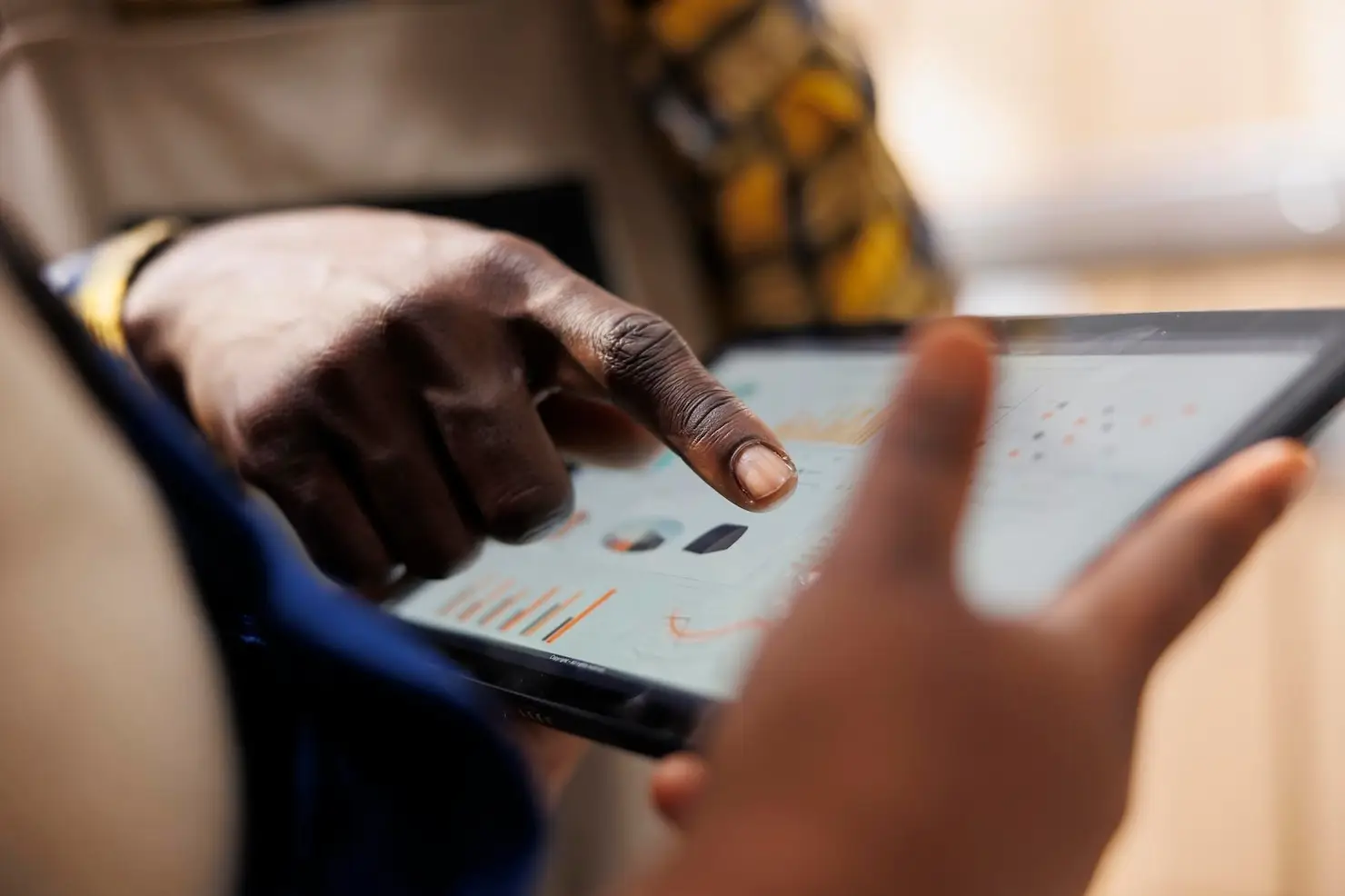 Finger pointing at data charts on a digital tablet screen indoors