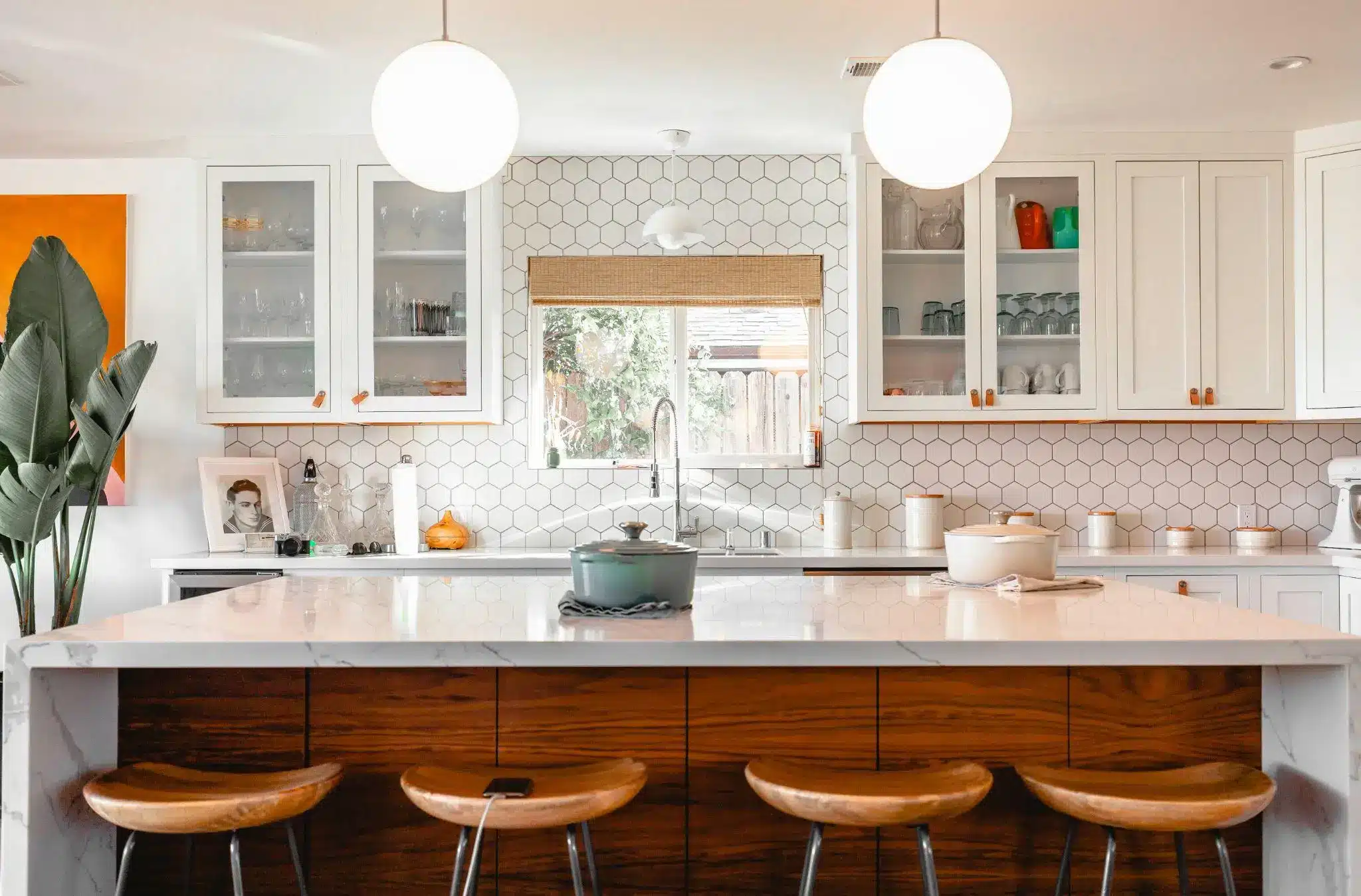 Modern kitchen with white cabinets, wooden bar stools, and hexagonal tile backsplash