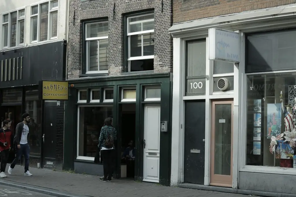 People walking past historic brick storefronts on urban street with shop signs and windows