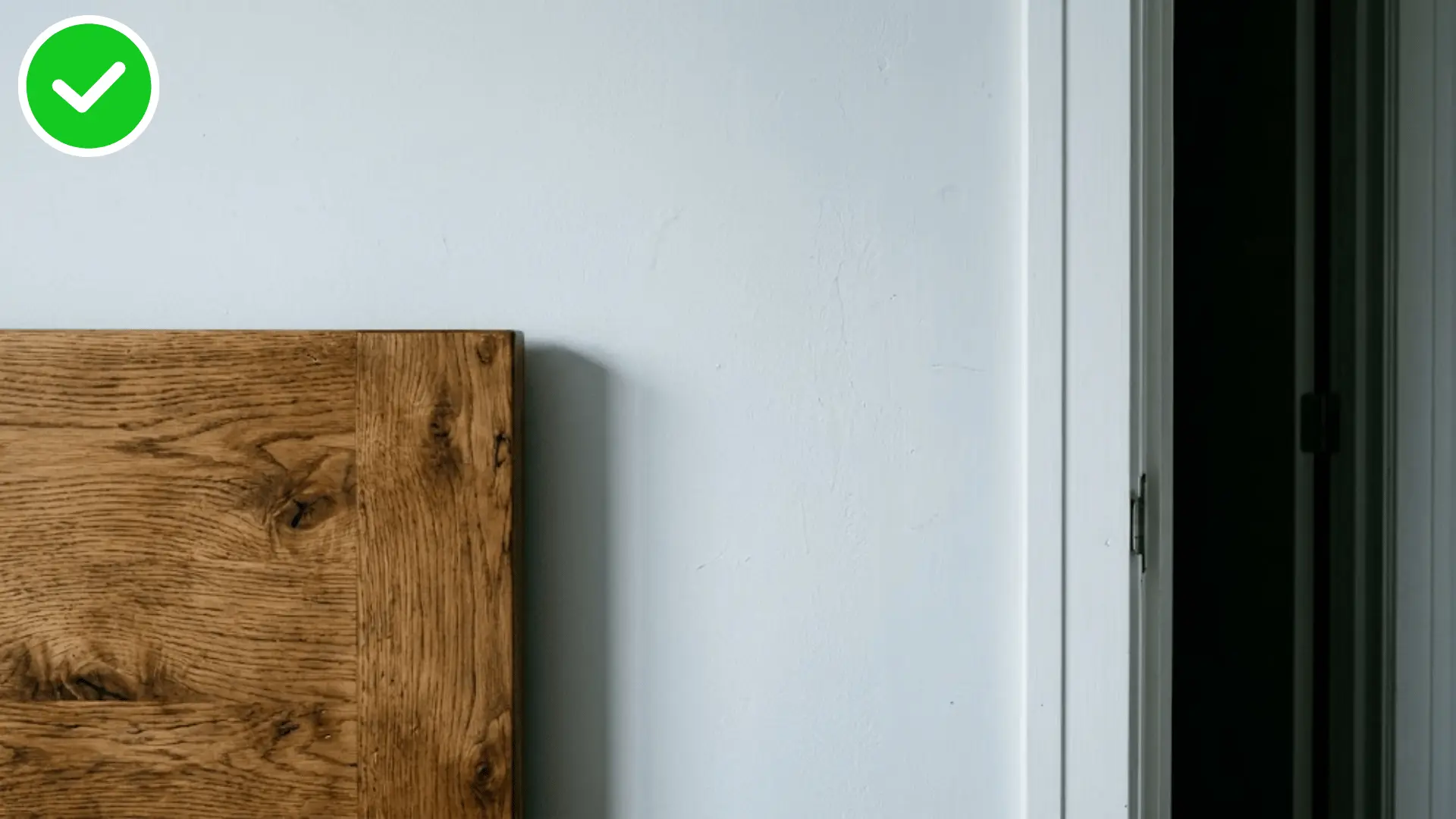 close up of a headboard against a solid wall with the open door edge in view