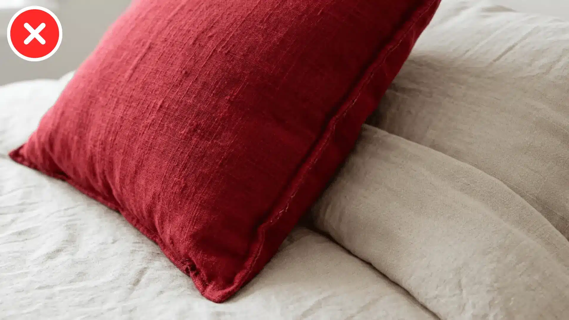 close up of one bold red pillow against plain neutral colored bedding