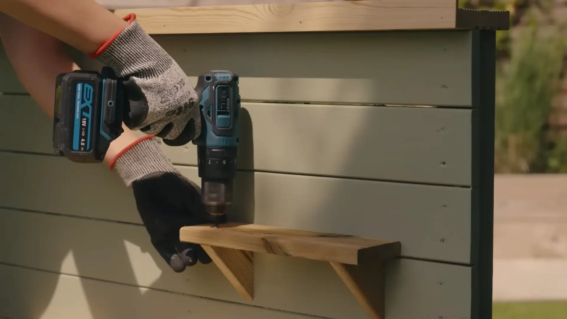 drilling pilot hole to attach wood shelf bracket to sage green mud kitchen back panel