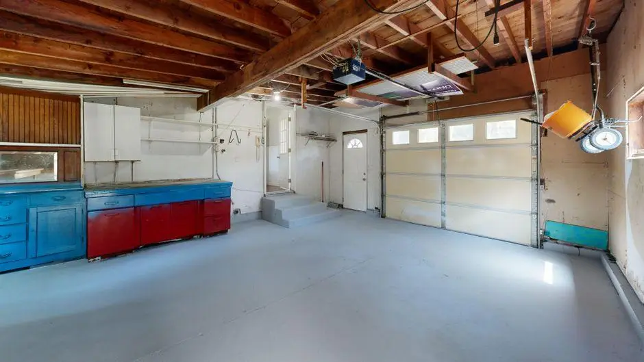 Spacious garage interior with colorful cabinets and exposed wooden beams under natural light