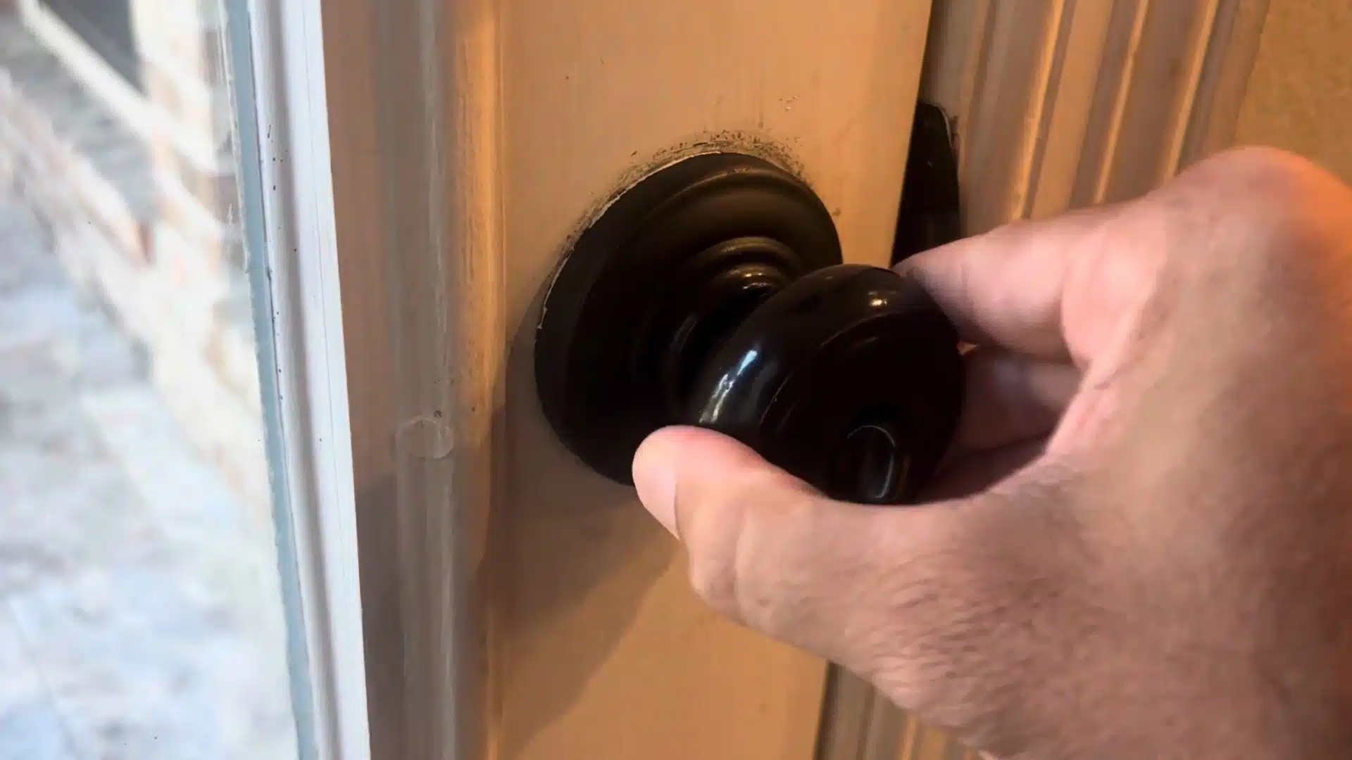 man testing the black door knob fit on the door after tightening the screws back