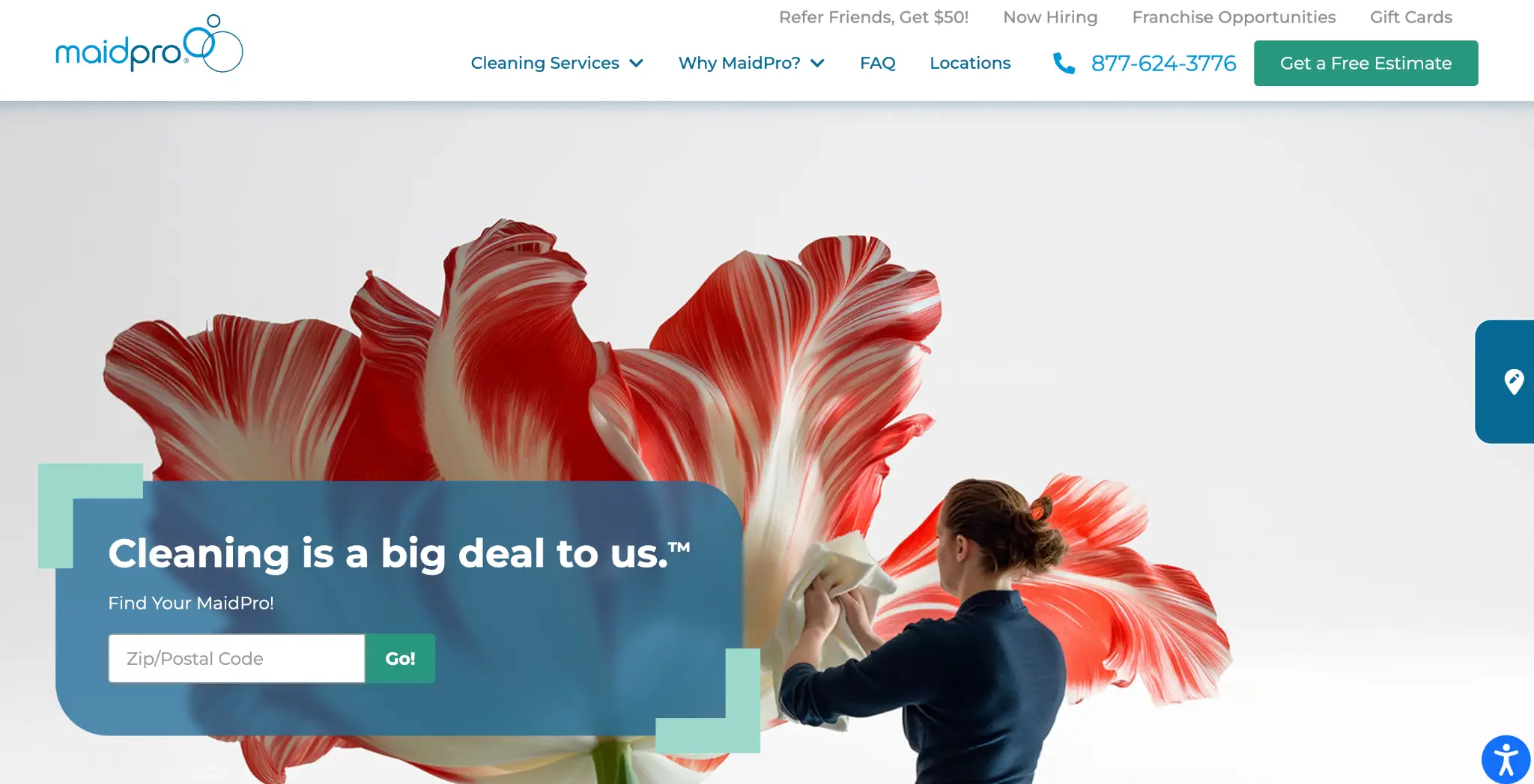 Person cleaning a giant red and white flower sculpture against a plain background