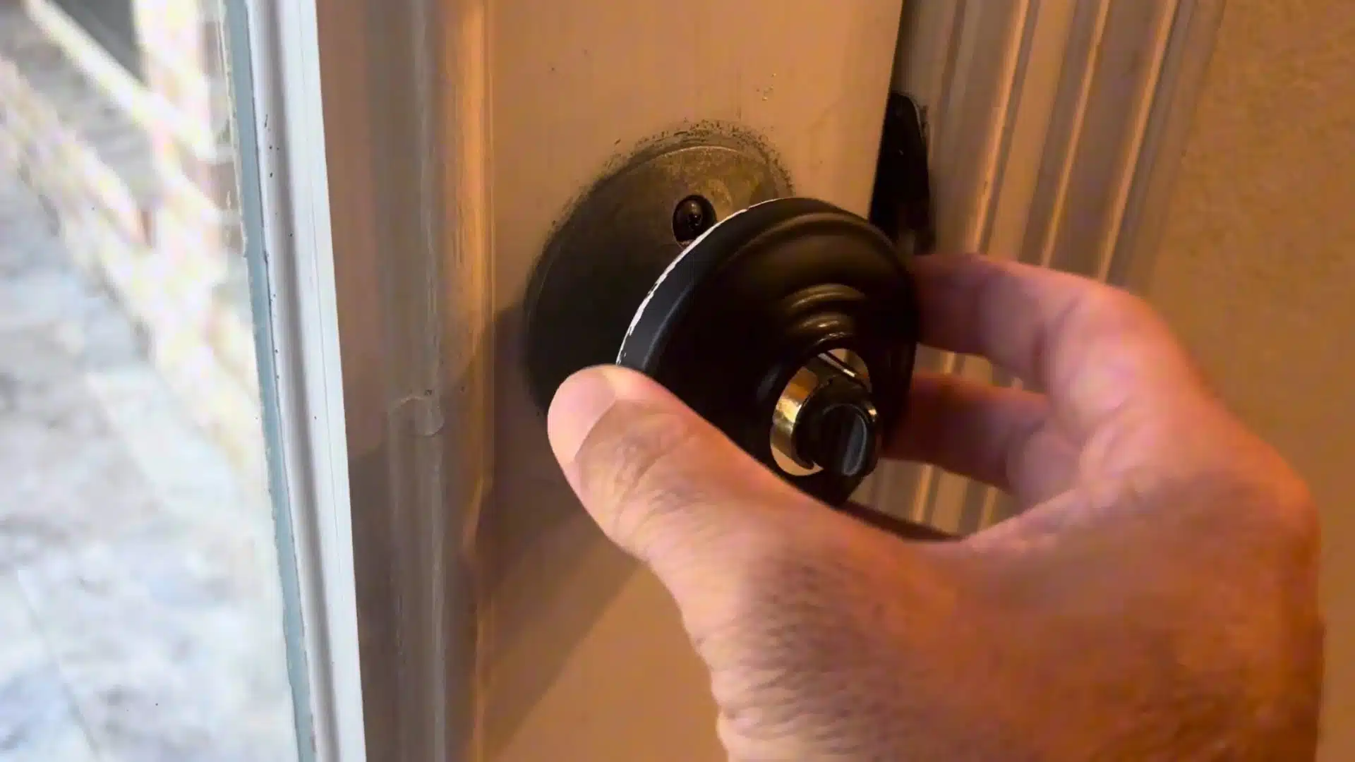 man fitting the black door knob back onto the spindle to reattach it to the door