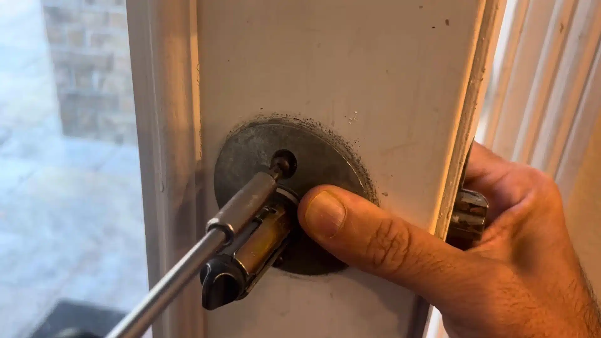 man holding the spindle mechanism steady while inserting a flathead screwdriver tip
