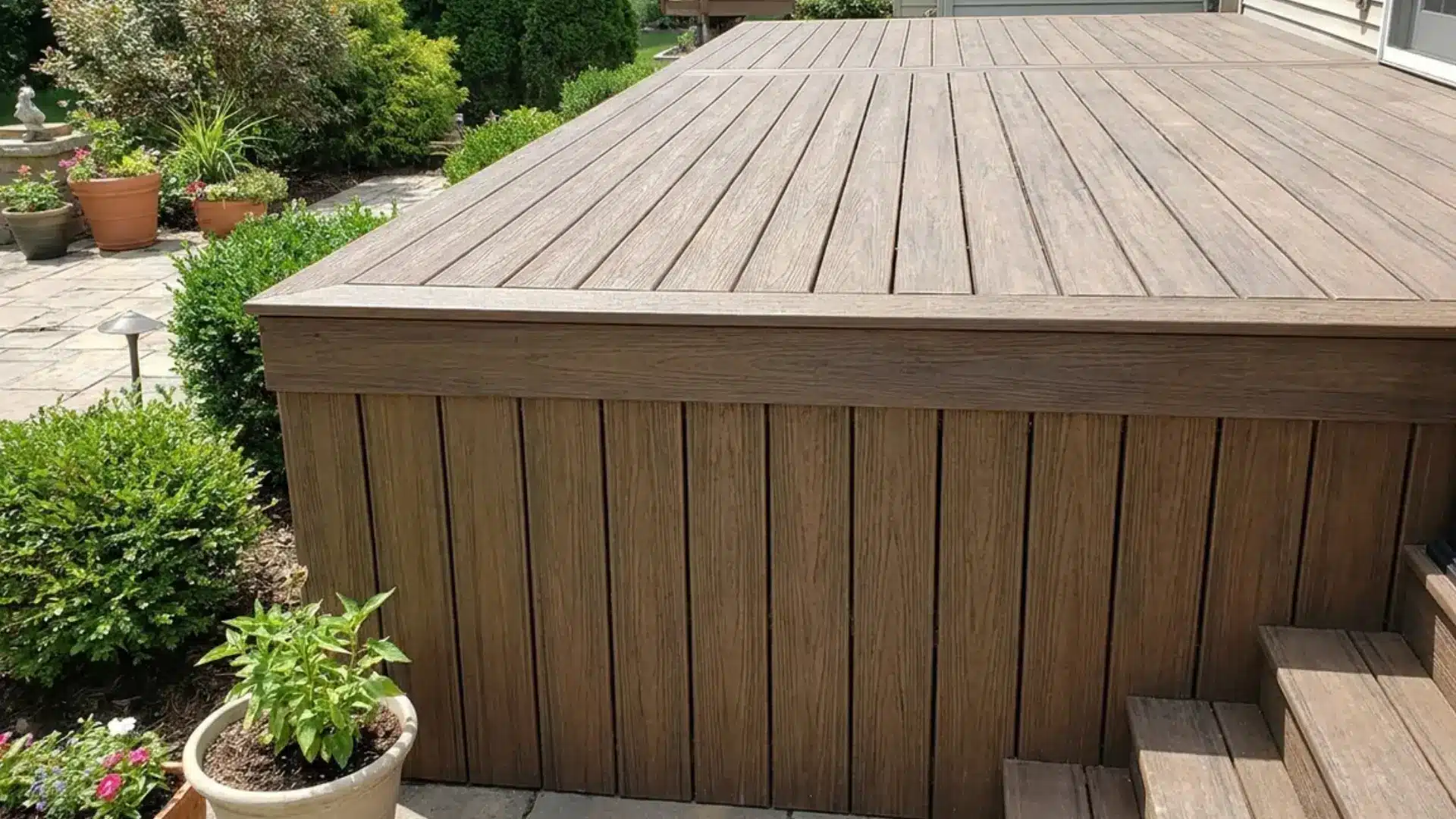 raised composite deck with matching vertical panel skirting and stone patio below