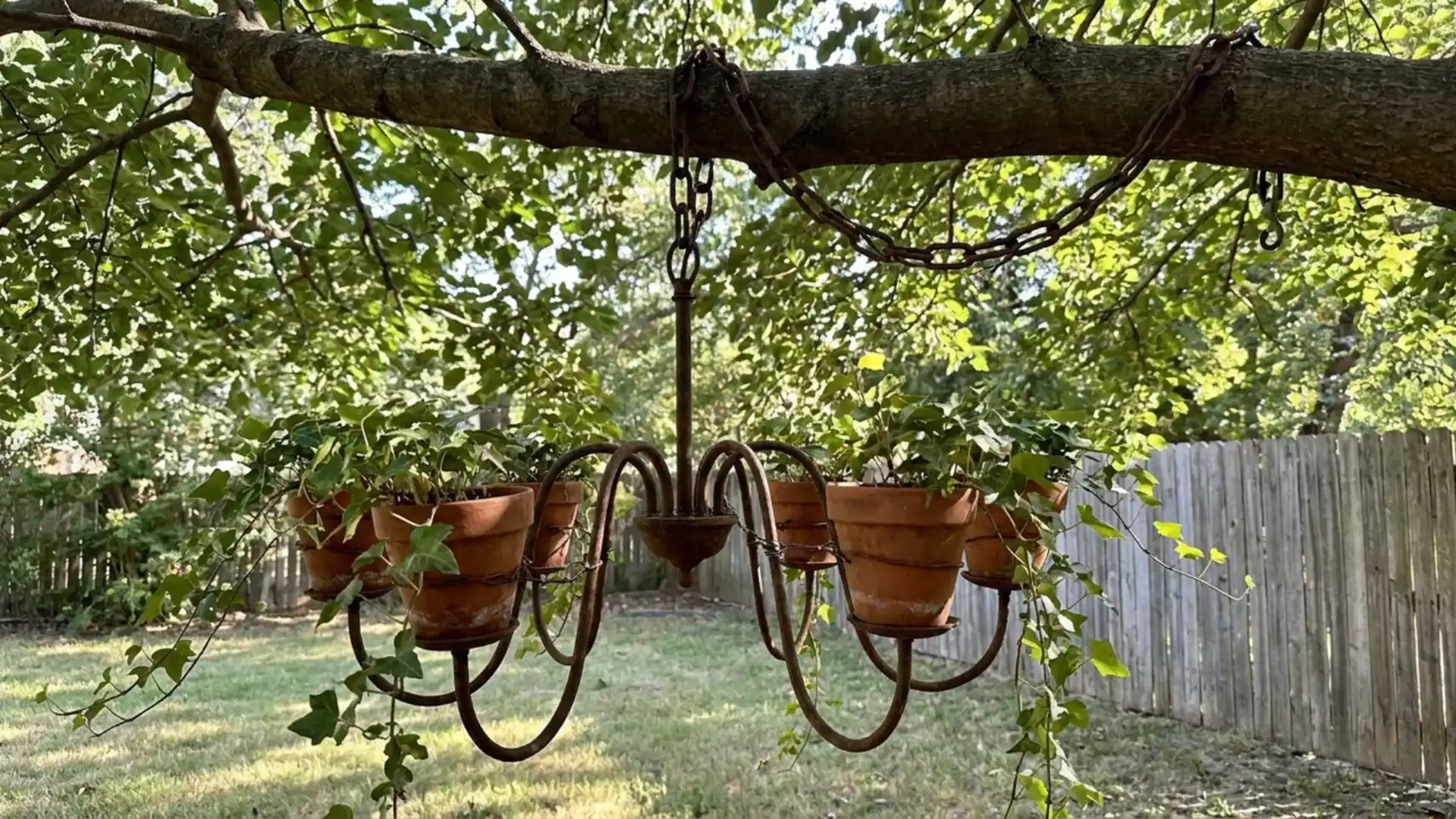 rustic metal chandelier planter with terracotta pots and ivy hanging from tree branch