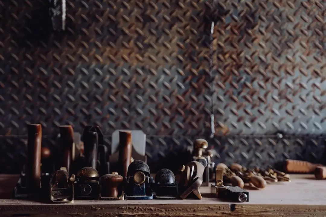 Vintage woodworking hand planes on wooden bench with textured metal wall background