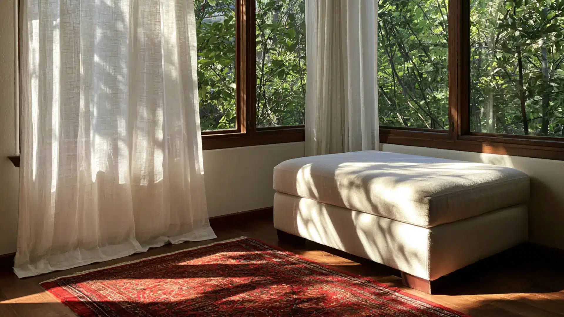 sheer curtains upholstered ottoman and layered rug near sunny window