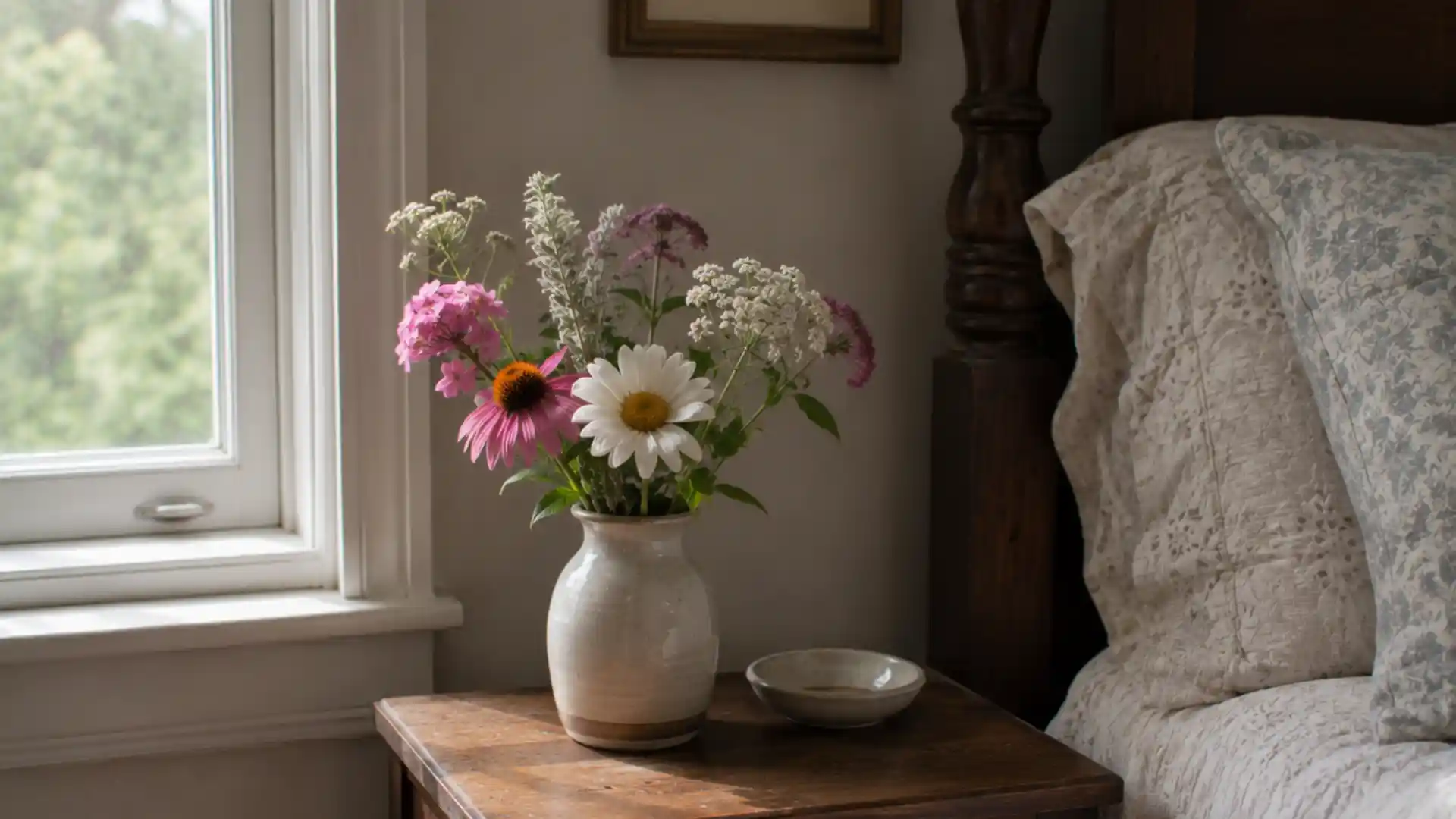 small vase of fresh garden flowers on a wooden bedside table