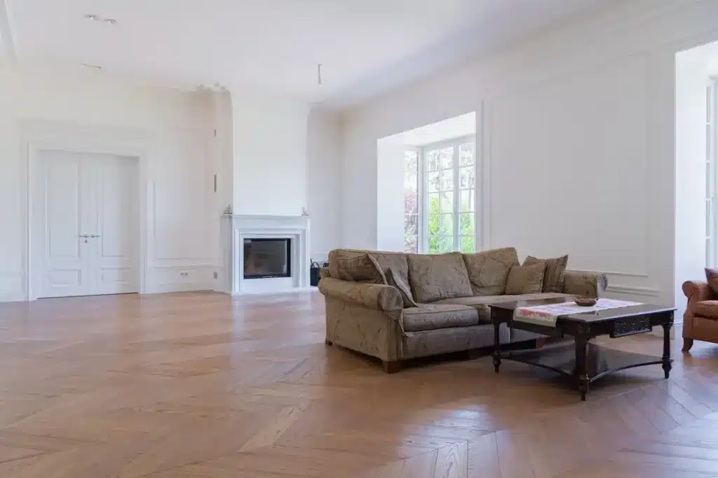 Spacious living room with patterned sofas, wooden coffee table, and large windows in bright setting