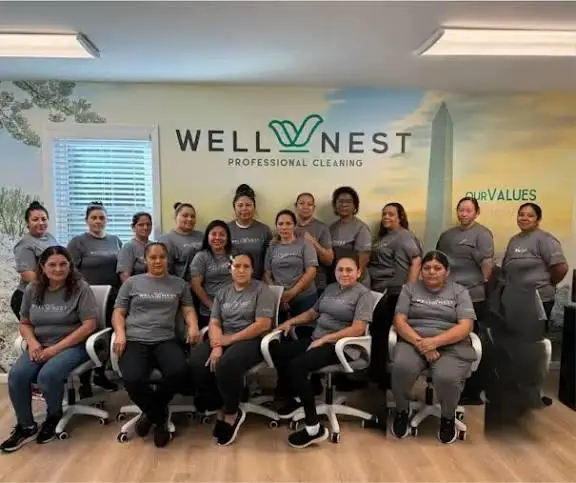 Group of people wearing matching t-shirts seated in office with company logo on wall