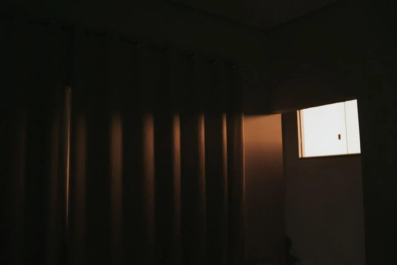 Dimly lit room with closed curtains and soft light coming through a window