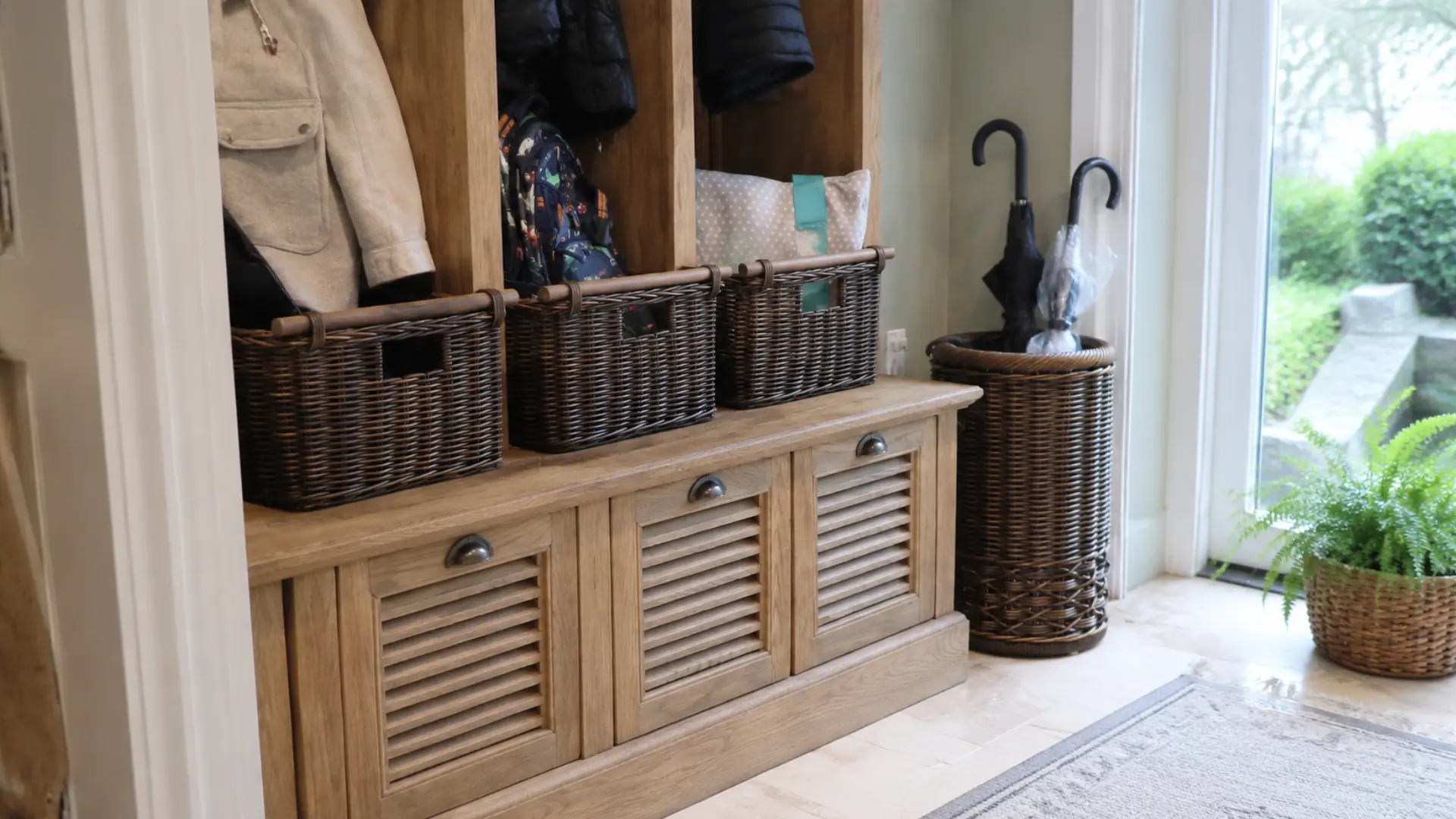wicker storage baskets holding coats and umbrellas in a sunroom entry nook