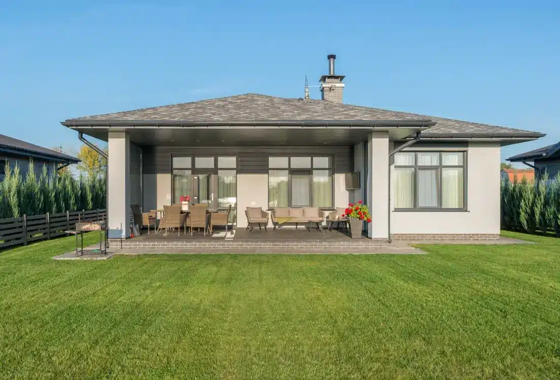 Single-story modern house with spacious backyard patio and outdoor seating arrangement