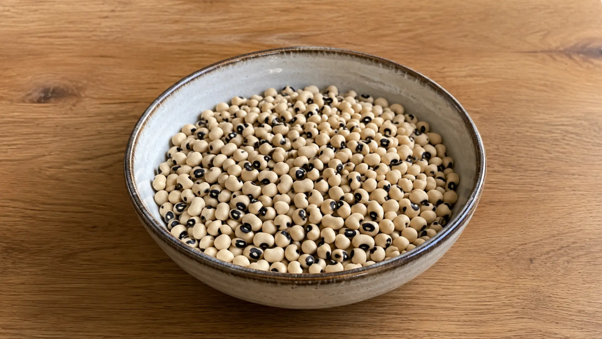 dry black-eyed peas with their dark spot in a kitchen bowl on a wodeen counter