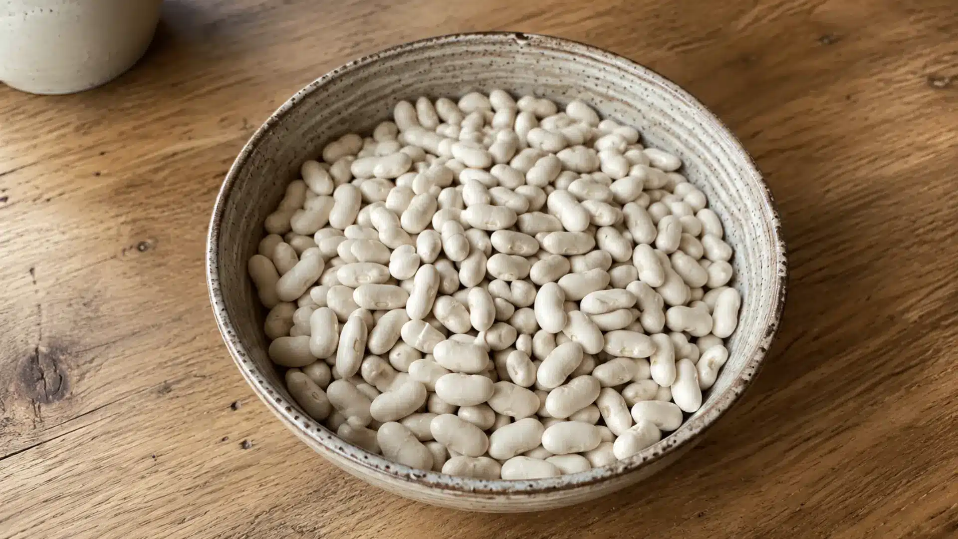 dry white cannellini beans in a ceramic bowl on a wood table