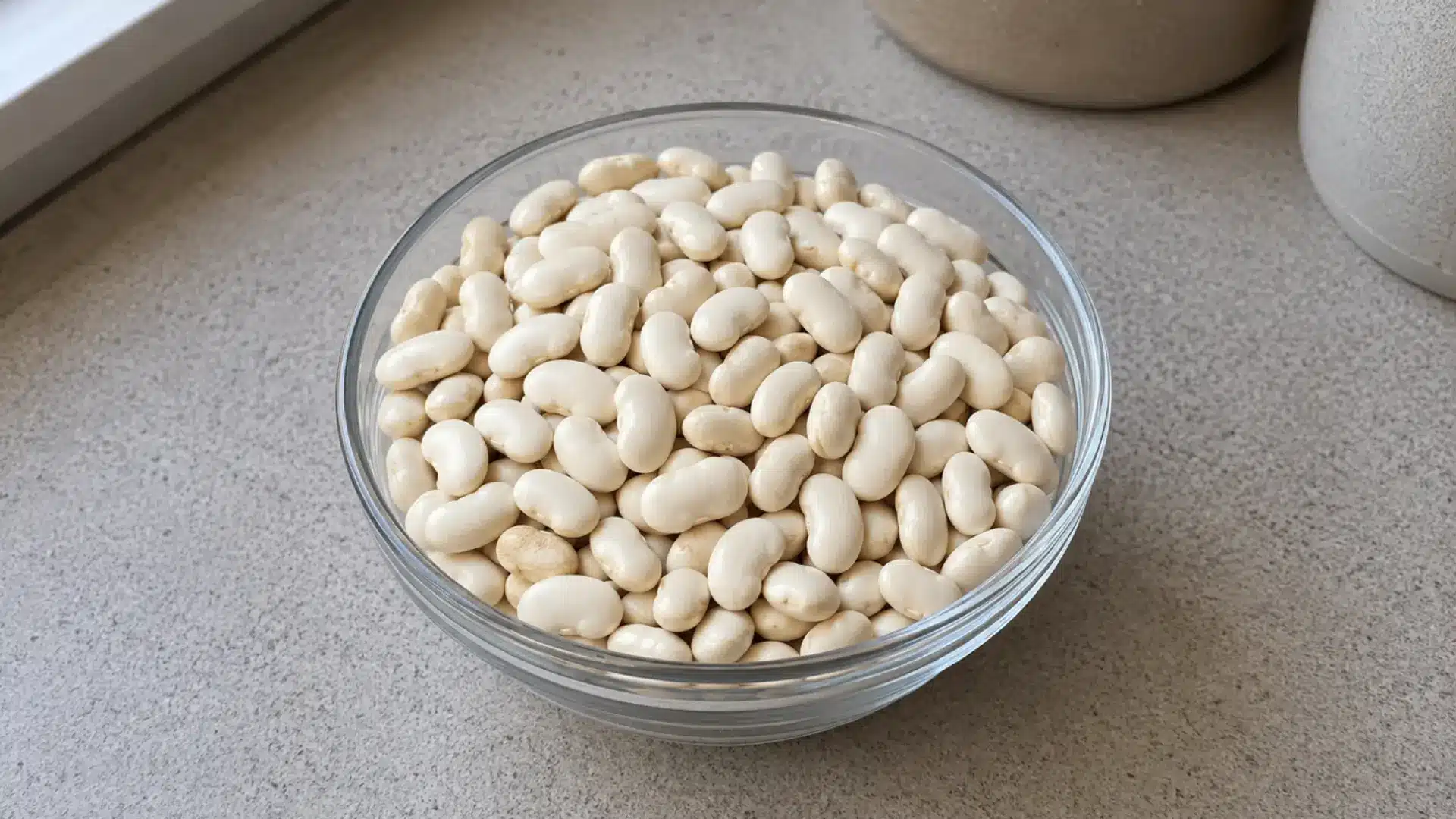 dry white great northern beans in a glass bowl on a kitchen counter