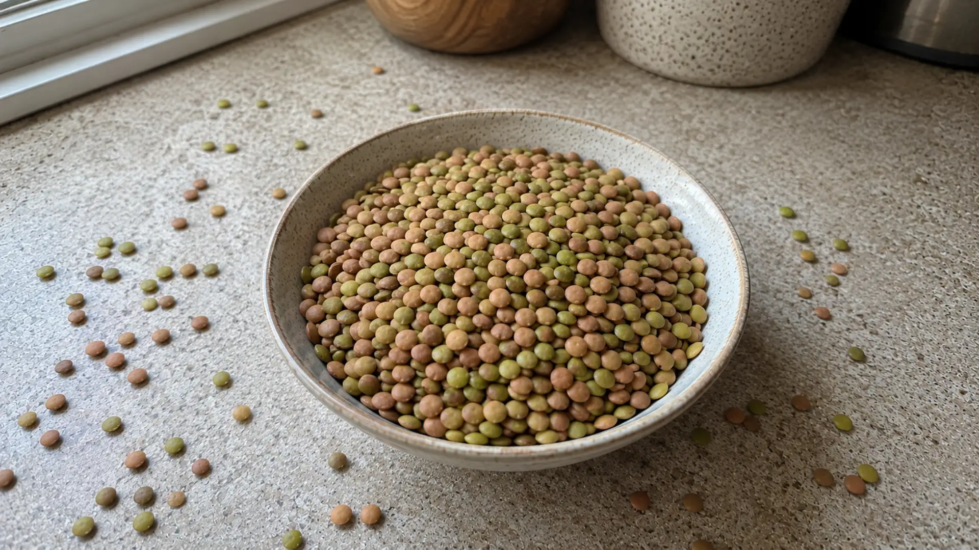 dry brown and green lentils in a bowl on a kitchen counter