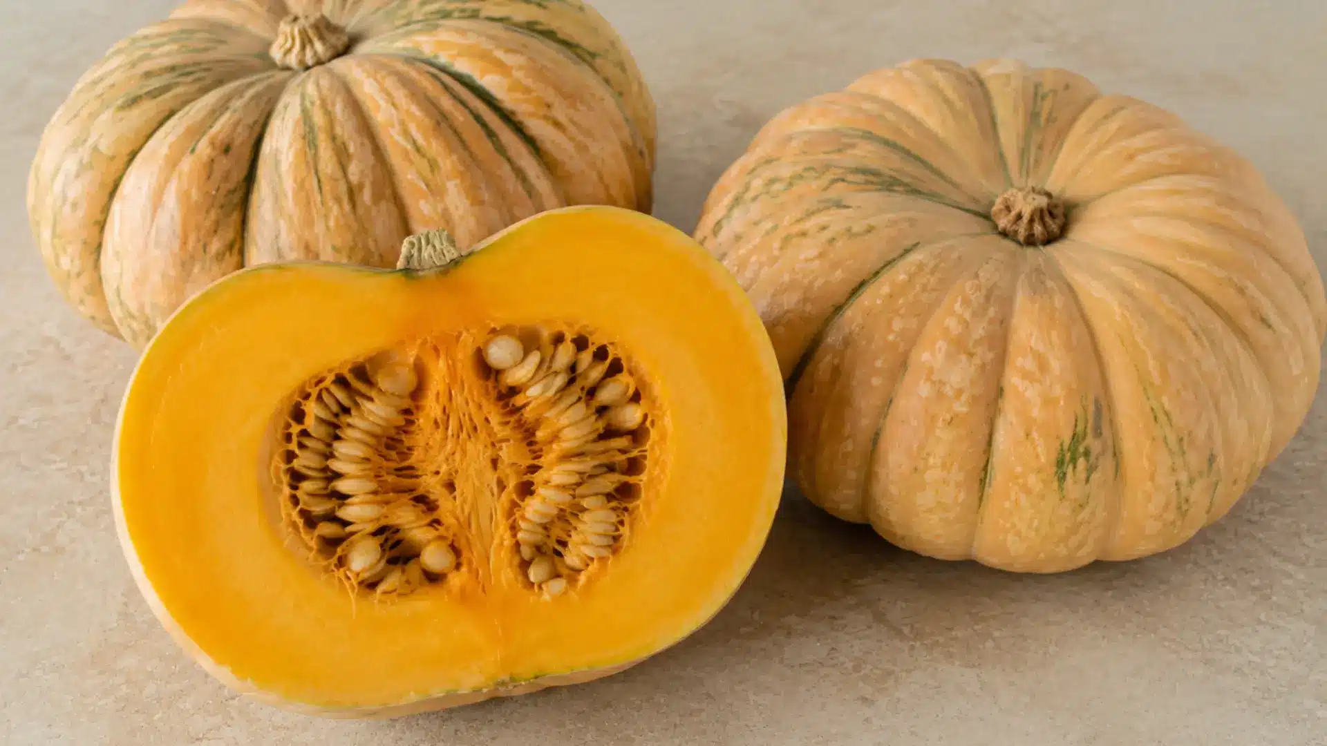 long island cheese pumpkin halved and whole on a kitchen slab