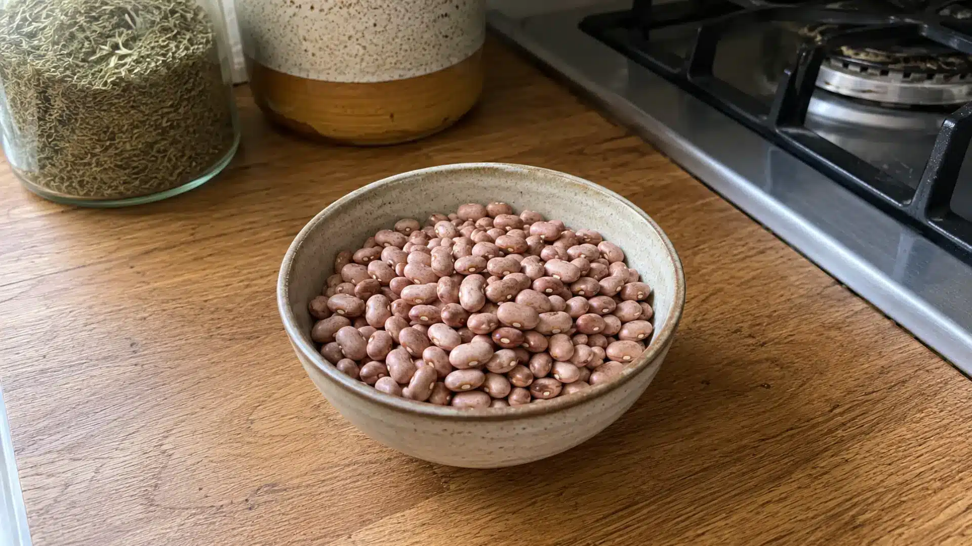dry pink beans in a small ceramic bowl on a kitchen wooden counter