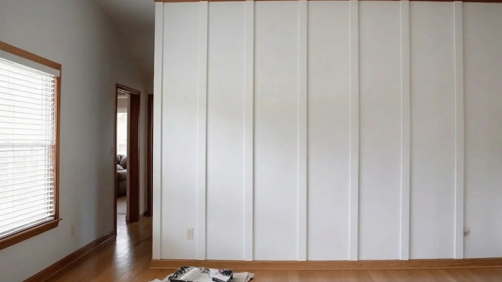 finished white board and batten accent wall with natural wood trim and painting supplies on a drop cloth.
