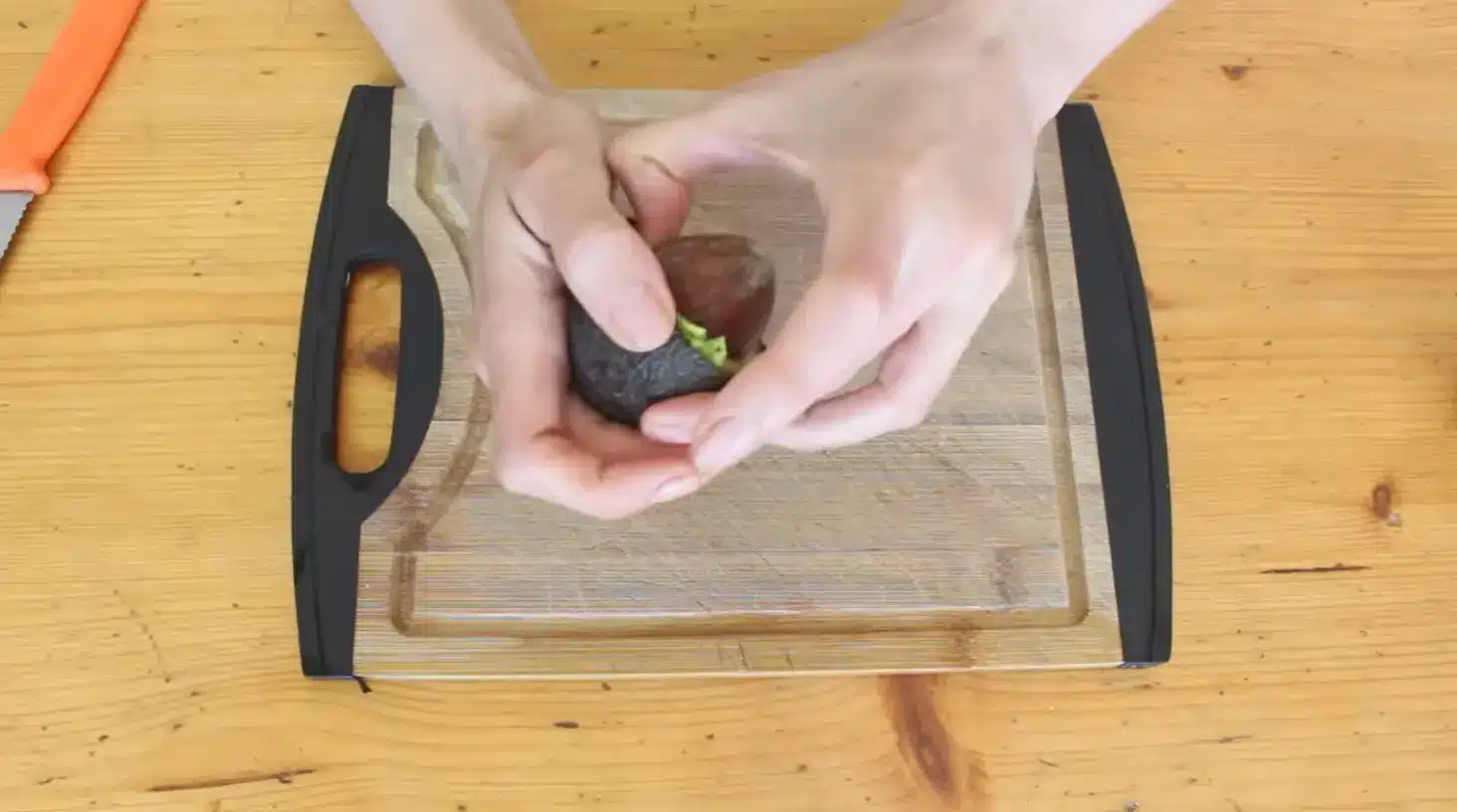 hands carefully removing an avocado seed from a freshly cut ripe avocado