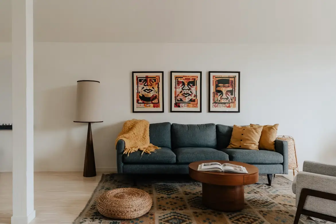 Mid-century modern living room with blue sofa, framed artwork, and wooden coffee table on patterned rug