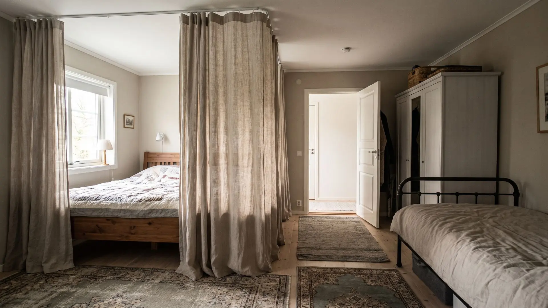 floor-length curtains dividing two sleeping areas while keeping the bedroom doorway accessible