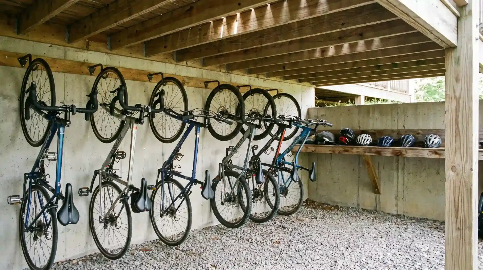 bicycles hanging vertically on wall-mounted racks with helmets stored beneath a raised wooden deck