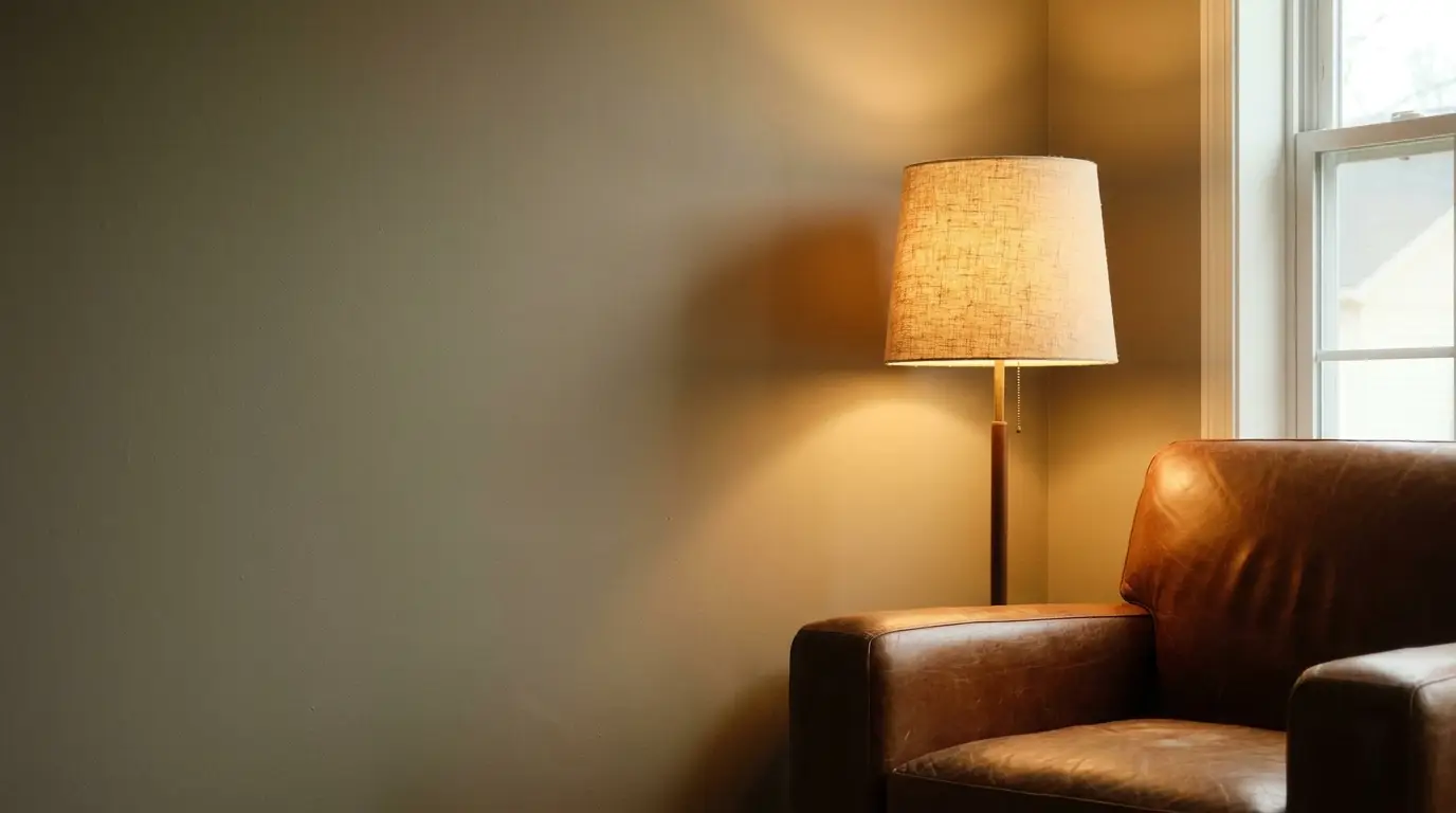Cozy reading corner with leather armchair and warm-lit floor lamp near a window