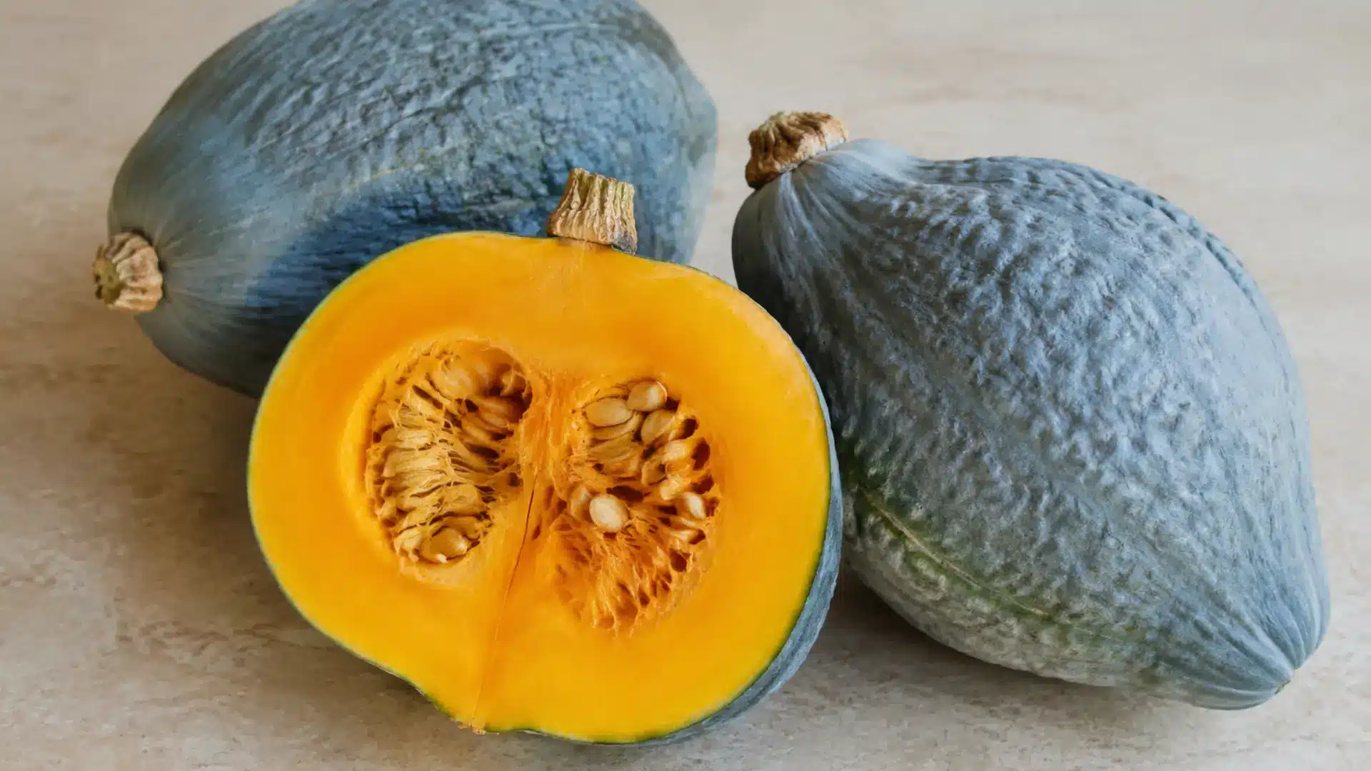 hubbard squash halved and whole on a kitchen slab